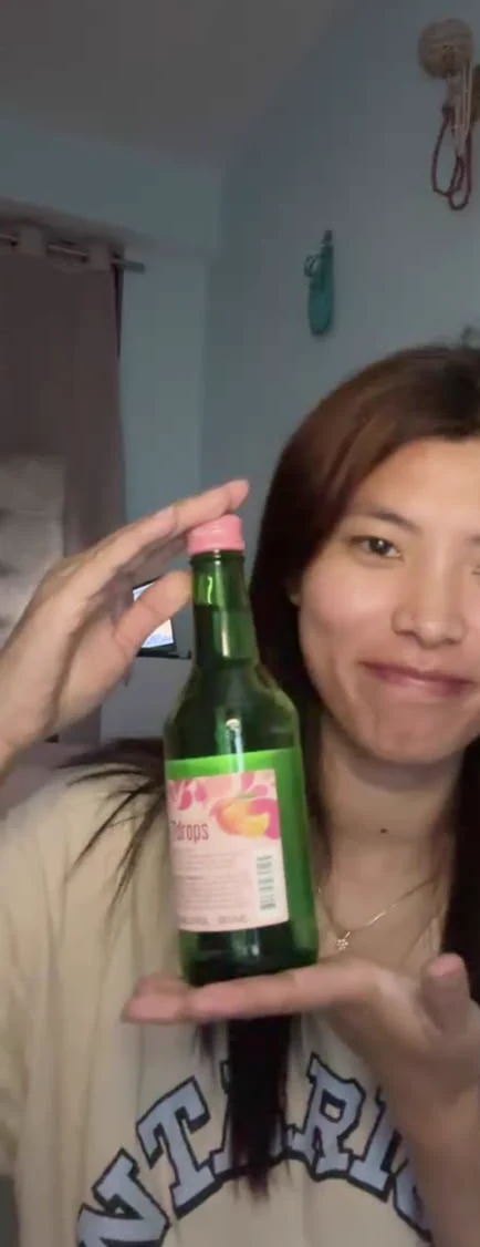 Sonam smiling while holding up a bottle during a video call.