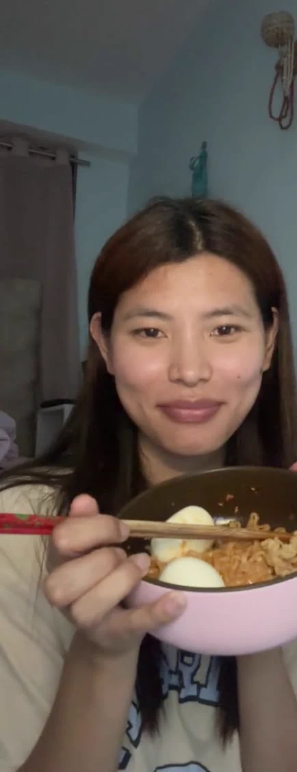Sonam on a video call while holding a bowl of food toward the camera.