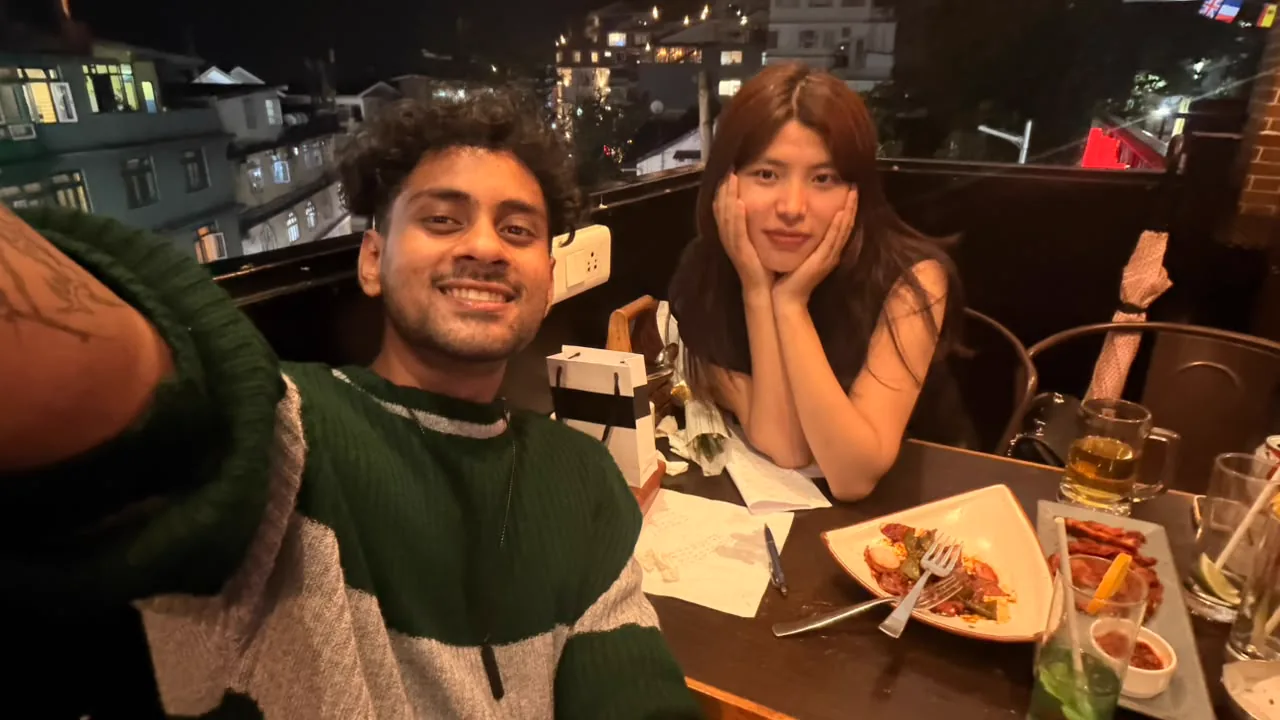 Saharsh and Sonam sitting close together at a restaurant table at night.