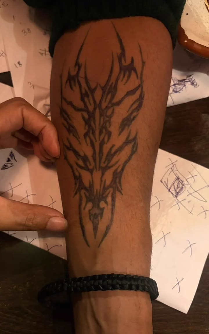 A close view of a temporary dark drawing on an arm above papers on the table.