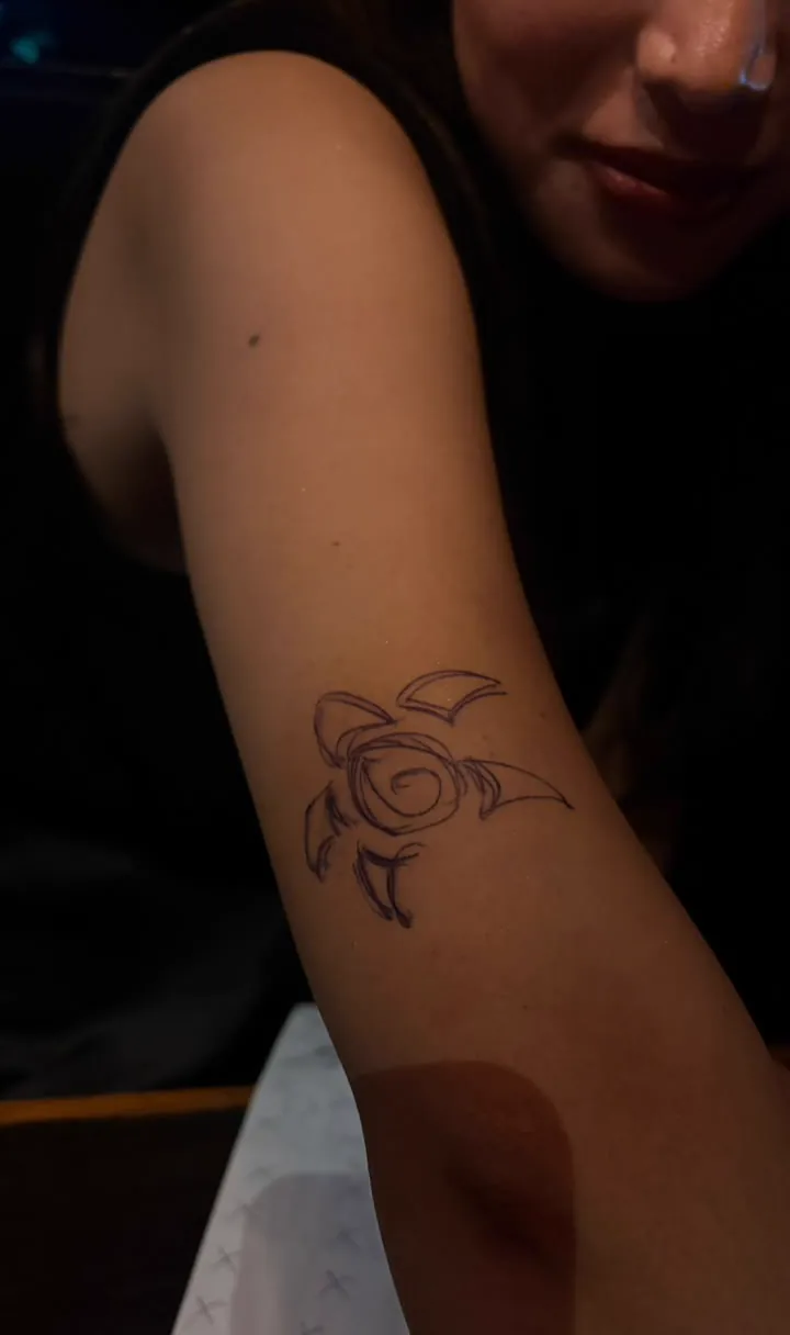 Sonam smiling beside a temporary leaf-like drawing on her arm.
