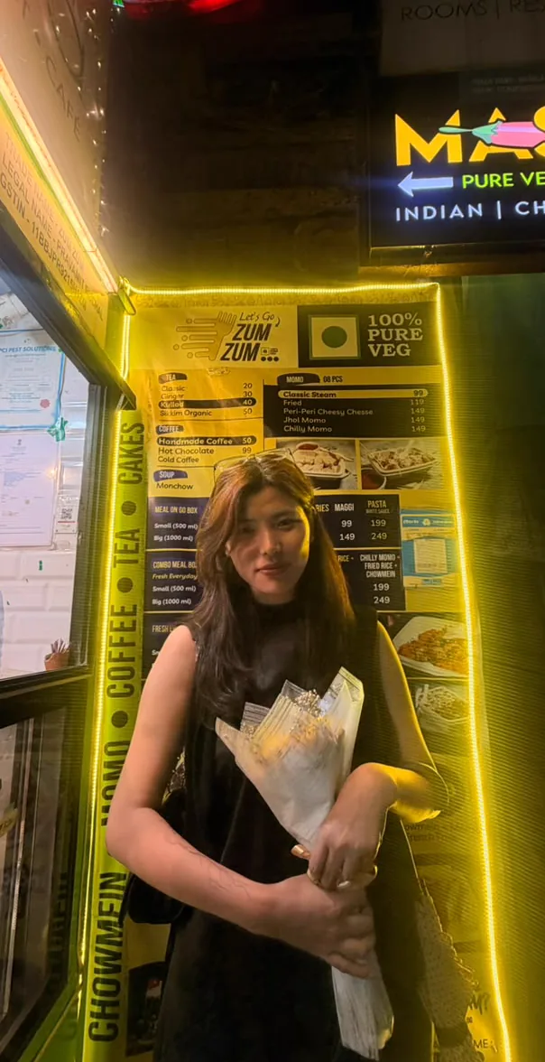 Sonam standing outside the restaurant while holding flowers.