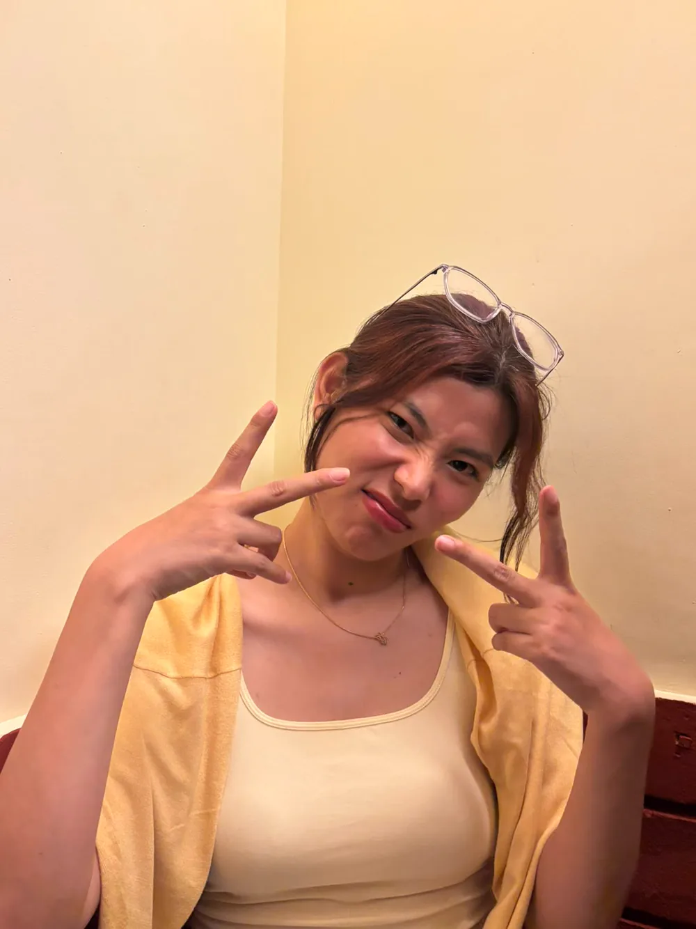 Sonam posing indoors with both hands making peace signs.